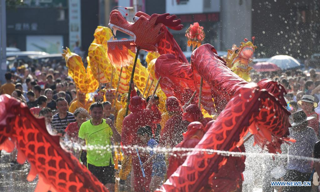 A dragon dance team performs amid splashes of water to celebrate 
