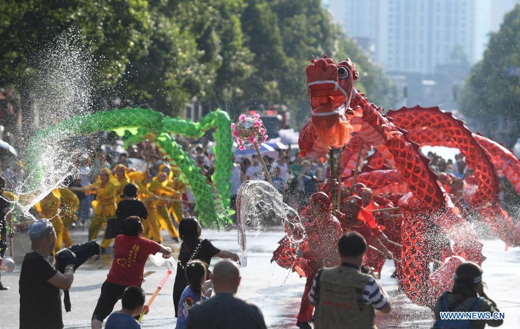 A dragon dance team performs amid splashes of water to celebrate 