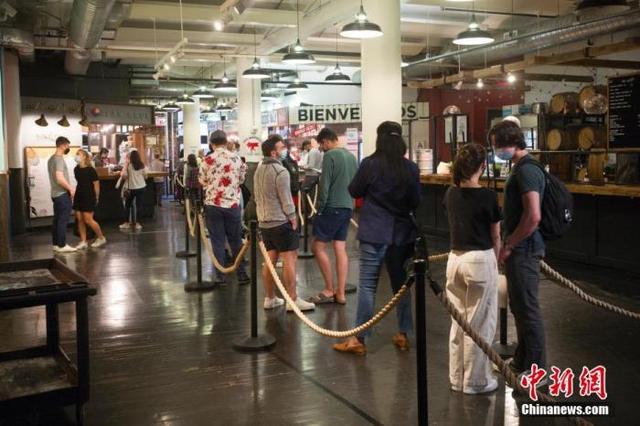 资料图:顾客在美国纽约切尔西市场一家餐厅排队购买餐食。自5月下旬纽约州博物馆、电影院、餐厅、零售业等商业和文化场所的客容量限制全面解除后,纽约著名的切尔西市场客流逐渐恢复。 中新社记者 廖攀 摄