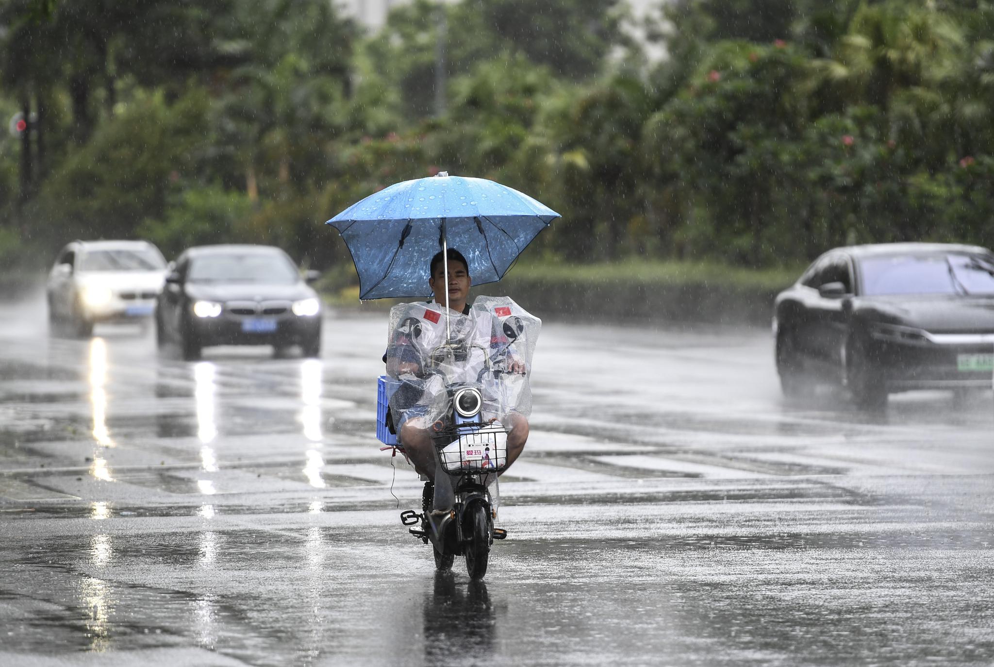 7月19日,居民骑着电动车在雨中前行.新华社记者 毛思倩 摄