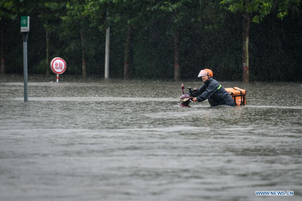 A courier wades through a waterlogged road in Zhengzhou, capital of central China's Henan Province, July 20, 2021. More than 144,660 residents have been affected by torrential rains in central China's Henan Province since July 16, and 10,152 have been relocated to safe places, the provincial flood control and drought relief headquarters said Tuesday. A total of 16 large and medium-sized reservoirs have seen water levels rise above the alert level after torrential rains battered most parts of the province on Monday and Tuesday. (Photo by Hou Jianxun/Xinhua)