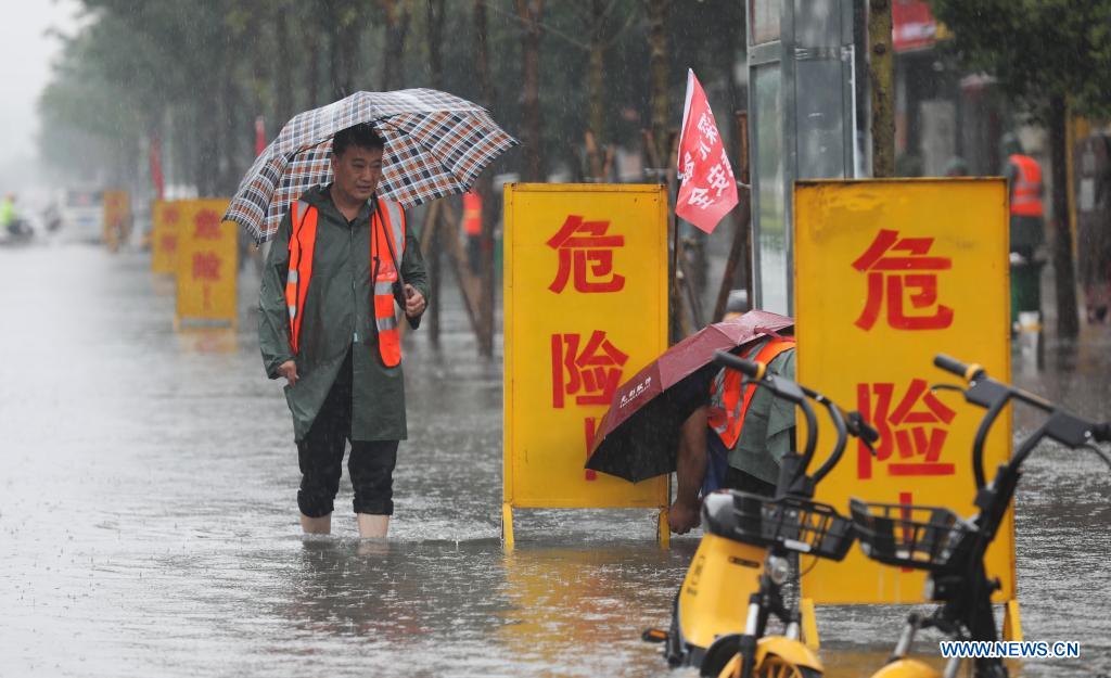 Staff members set up warning signs at a waterlogged area in Wuzhi County, central China's Henan Province, July 20, 2021. Wuzhi County of Jiaozuo has recently witnessed continuous rainfalls. Flood-control measures such as water draining, patrolling embankments and traffic control were carried out to protect the safety of people's lives and property. (Photo by Feng Xiaomin/Xinhua)