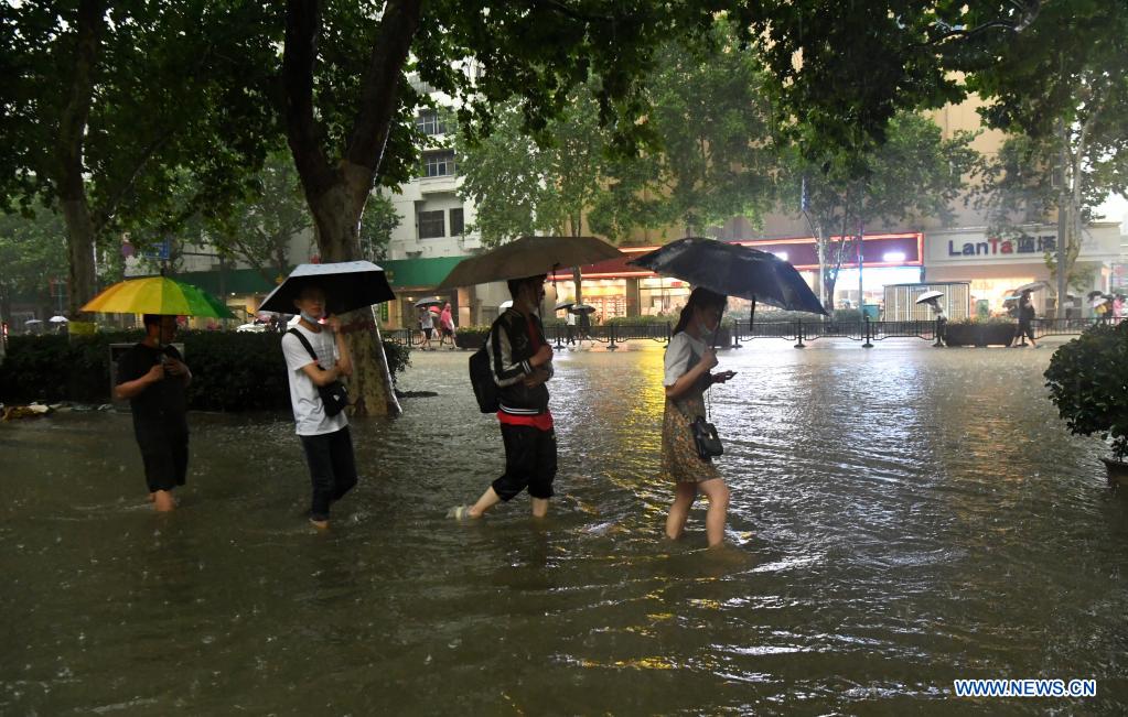 People wade through a waterlogged road in Zhengzhou, capital of central China's Henan Province, July 20, 2021. More than 144,660 residents have been affected by torrential rains in central China's Henan Province since July 16, and 10,152 have been relocated to safe places, the provincial flood control and drought relief headquarters said Tuesday. A total of 16 large and medium-sized reservoirs have seen water levels rise above the alert level after torrential rains battered most parts of the province on Monday and Tuesday. (Xinhua/Zhu Xiang)