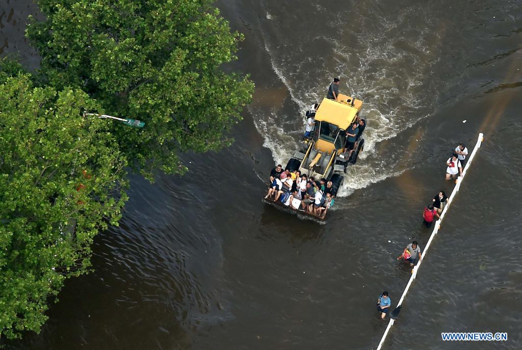 Stranded residents are evacuated on a shovel loader in flood-hit Weihui City, central China's Henan Province, July 24, 2021. (Xinhua/Li An)