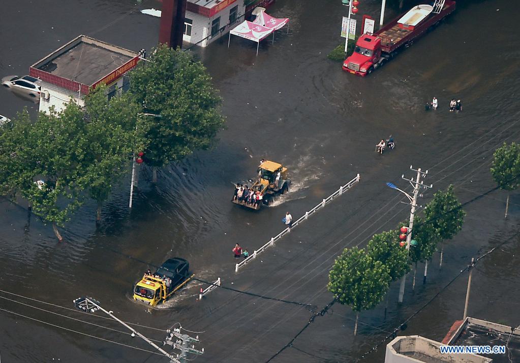 Stranded residents are evacuated on a truck and a shovel loader in flood-hit Weihui City, central China's Henan Province, July 24, 2021. (Xinhua/Li An)