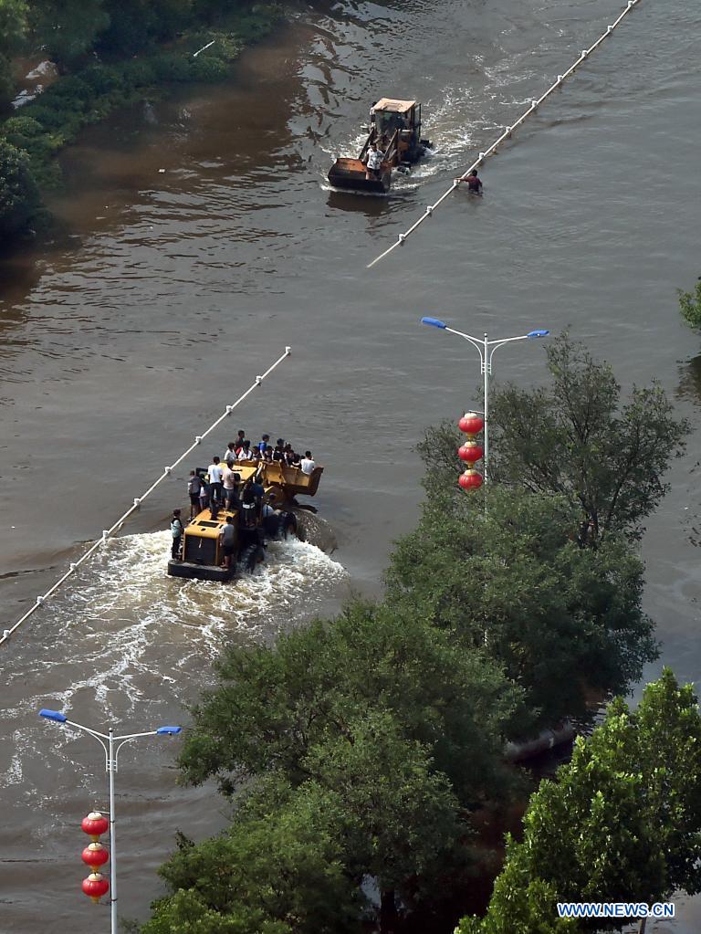 Stranded residents are evacuated on shovel loaders in flood-hit Weihui City, central China's Henan Province, July 24, 2021. (Xinhua/Li An)