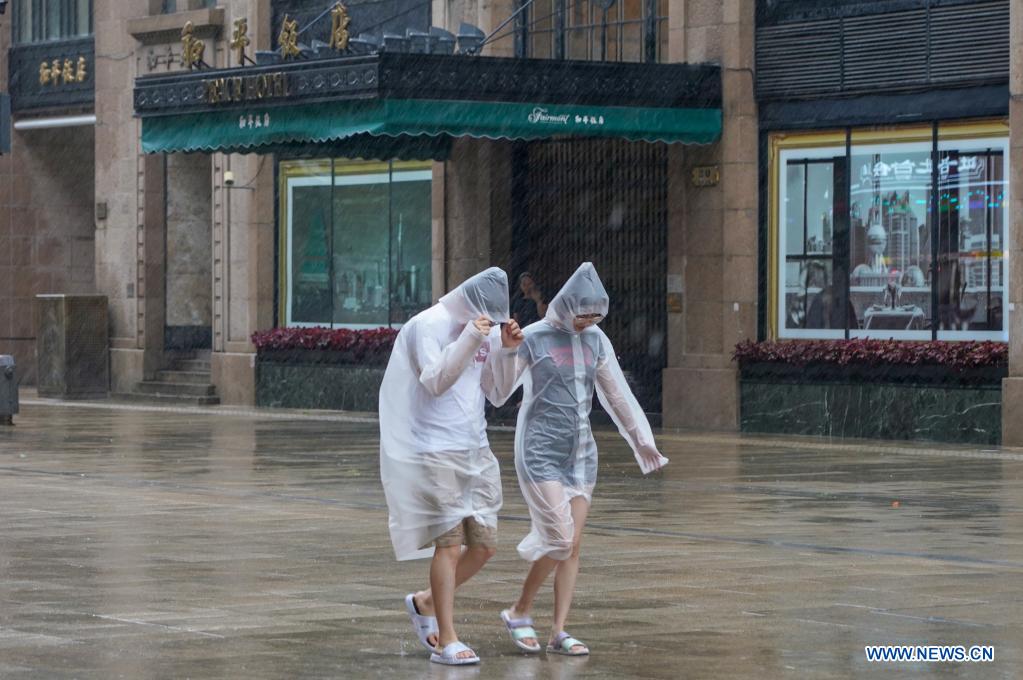 Pedestrians walk against gales at Nanjing Rd. Pedestrian Mall in east China's Shanghai, July 25, 2021. Typhoon In-Fa, which made landfall in east China's Zhejiang Province at around Sunday noon, will make another landfall in coastal areas from Pinghu in Zhejiang Province to Pudong in Shanghai, according to the National Meteorological Center. (Xinhua/Wang Xiang)