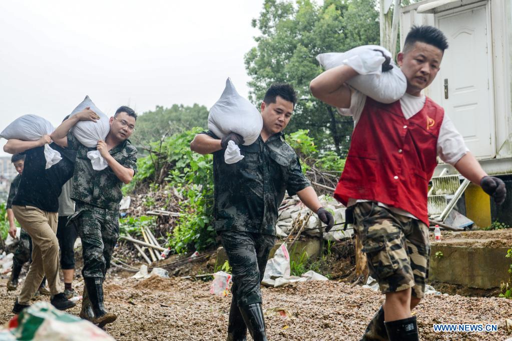 People carry sandbags to reinforce river banks in Changxing County of Huzhou City, east China's Zhejiang Province, July 25, 2021. China's national observatory on Sunday continued its orange alert for Typhoon In-Fa, which made landfall in Zhejiang at around Sunday noon. (Photo by Wu Zheng/Xinhua)