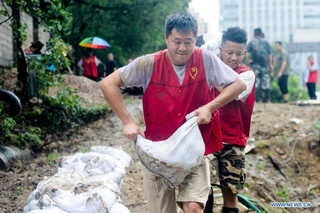 People carry sandbags to reinforce river banks in Changxing County of Huzhou City, east China's Zhejiang Province, July 25, 2021. China's national observatory on Sunday continued its orange alert for Typhoon In-Fa, which made landfall in Zhejiang at around Sunday noon. (Photo by Wu Zheng/Xinhua)
