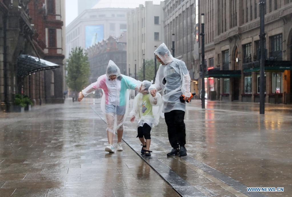 Pedestrians walk at Nanjing Rd. Pedestrian Mall in east China's Shanghai, July 25, 2021. Typhoon In-Fa, which made landfall in east China's Zhejiang Province at around Sunday noon, will make another landfall in coastal areas from Pinghu in Zhejiang Province to Pudong in Shanghai, according to the National Meteorological Center. (Xinhua/Fang Zhe)