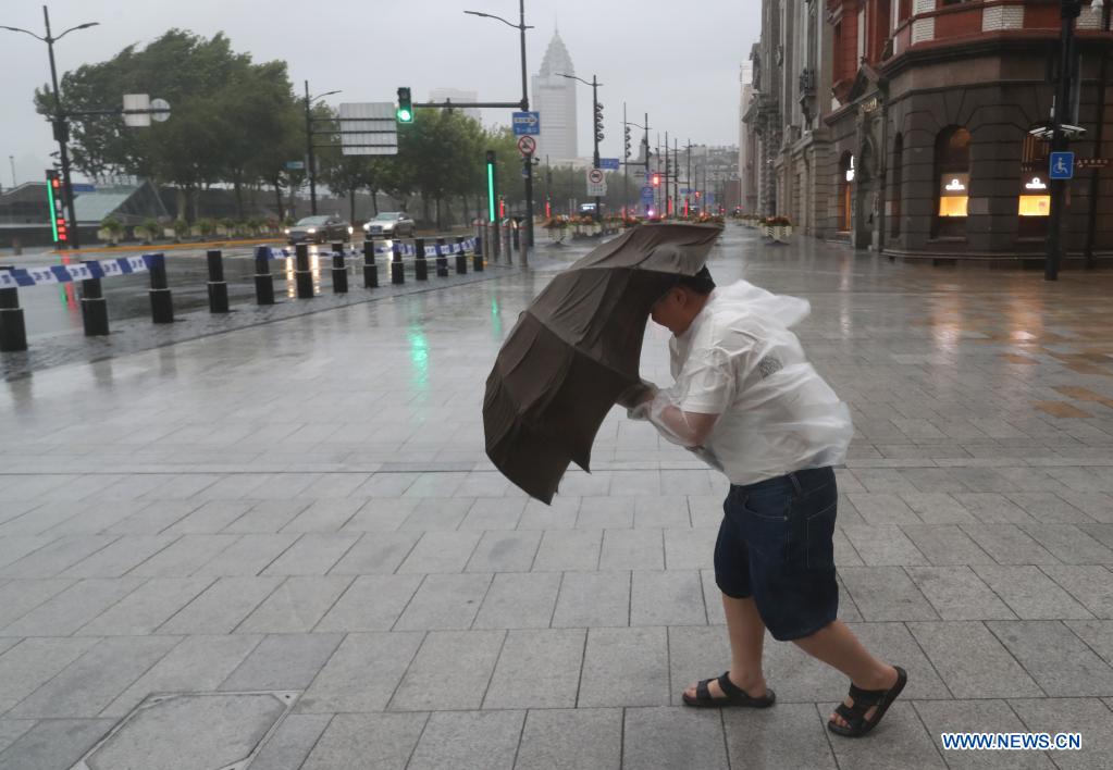 A pedestrian walks against gales on a road in Minhang District in east China's Shanghai, July 25, 2021. Typhoon In-Fa, which made landfall in east China's Zhejiang Province at around Sunday noon, will make another landfall in coastal areas from Pinghu in Zhejiang Province to Pudong in Shanghai, according to the National Meteorological Center. (Xinhua/Fang Zhe)