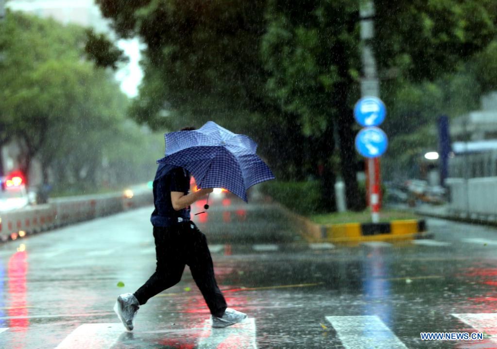 A pedestrian walks against gales on a road in Minhang District in east China's Shanghai, July 25, 2021. Typhoon In-Fa, which made landfall in east China's Zhejiang Province at around Sunday noon, will make another landfall in coastal areas from Pinghu in Zhejiang Province to Pudong in Shanghai, according to the National Meteorological Center. (Xinhua/Liu Ying)