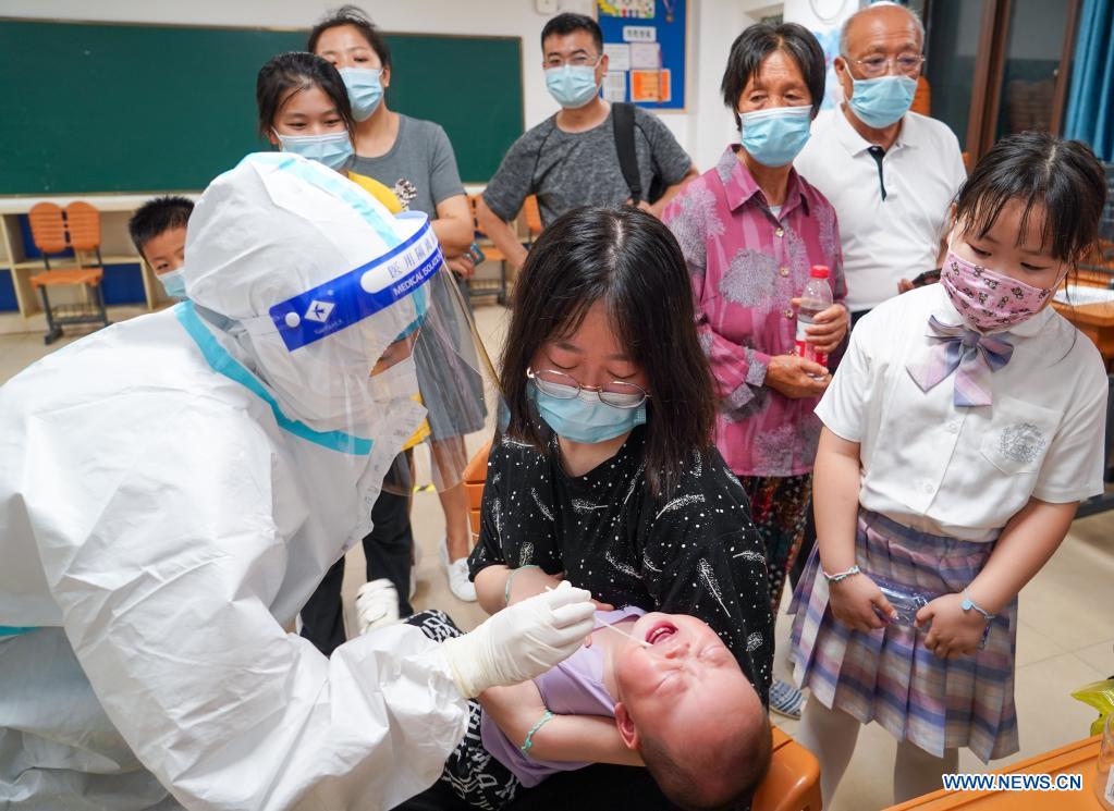 A medical worker takes a swab sample from a child for COVID-19 test at a testing site in Jiangning District of Nanjing, capital of east China's Jiangsu Province, July 24, 2021. Nanjing, a mega-city with a population of more than 9.3 million, has launched a second round of all-inclusive nucleic acid testing and urged residents not to leave the city unless necessary. (Xinhua/Li Bo)
