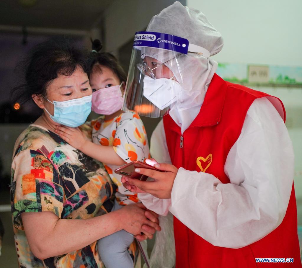 A volunteer (R) helps residents make COVID-19 test reservations at a COVID-19 testing site in Jiangning District of Nanjing, capital of east China's Jiangsu Province, July 24, 2021. Nanjing, a mega-city with a population of more than 9.3 million, has launched a second round of all-inclusive nucleic acid testing and urged residents not to leave the city unless necessary. (Xinhua/Li Bo)