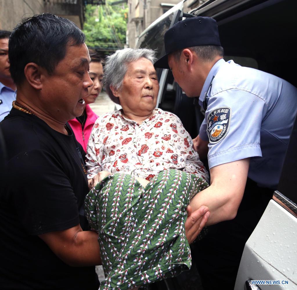 Policemen transfer a paralyzed woman in her eighties, in Qiyuan Township, Deqing County of Huzhou City, east China's Zhejiang Province, July 25, 2021. China's national observatory on Sunday continued its orange alert for Typhoon In-Fa, which made landfall in Zhejiang at around Sunday noon. (Photo by Ni Lifang/Xinhua)