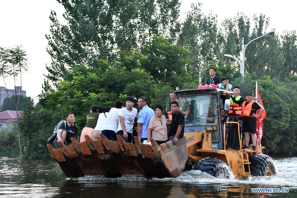 Stranded residents are transferred to safe areas aboard a shovel loader in Weihui, Xinxiang City of central China's Henan Province, July 26, 2021. Weihui is suffering from serious flooding caused by heavy downpour in the past few days. Rescue work is still in progress there. (Xinhua/Li Jianan)