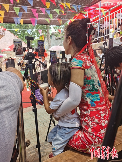 7月12日,一名主播抱着另一位主播的孩子在直播“拉面哥”。中青报·中青网记者 耿学清/摄