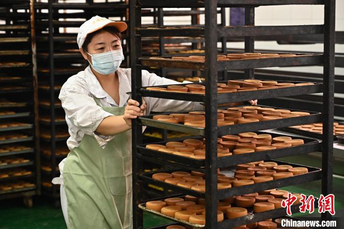 工人将烤熟的晋式月饼推往封包车间。 韦亮 摄