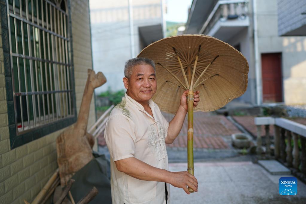 Li Nian'gen shows a bamboo umbrella, one of his bamboo-weaving products, in Dongcun Township, Fenyi County, Xinyu City of east China's Jiangxi Province, Sept. 1, 2021. Li Nian'gen, 62, is the fifth-generation inheritor of bamboo-weaving techniques in Dongcun Township. Li acquired bamboo-weaving techniques from his uncle when he was barely nine years old, and started to make a living on his own at the age of 15. More than 20 of his apprentices chose to seek employment for better income in other walks of life away from home in early 1990s, but Li decided to stay and stick to his profession. Li occasionally demonstrated his bamboo-weaving techniques on a video clip platform as suggested by others in 2019, and became increasingly popular ever since then. Now Li has more than 8 million followers on different platforms, with his short videos popular among netizens. (Xinhua/Zhou Mi)