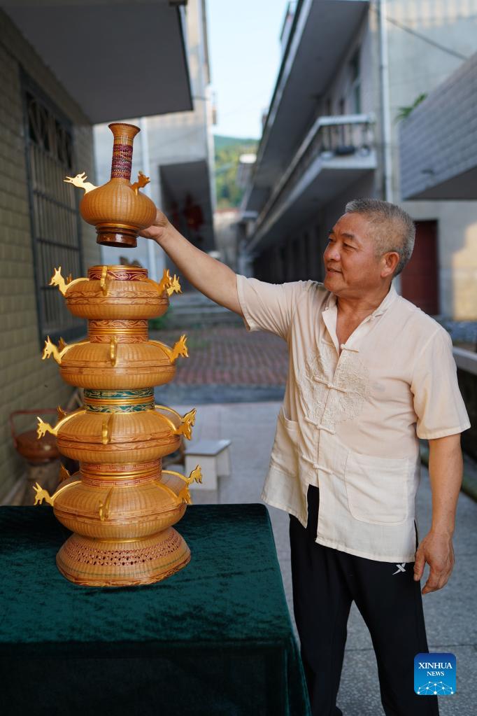 Li Nian'gen shows one of his bamboo-weaving products in Dongcun Township, Fenyi County, Xinyu City of east China's Jiangxi Province, Sept. 1, 2021. Li Nian'gen, 62, is the fifth-generation inheritor of bamboo-weaving techniques in Dongcun Township. Li acquired bamboo-weaving techniques from his uncle when he was barely nine years old, and started to make a living on his own at the age of 15. More than 20 of his apprentices chose to seek employment for better income in other walks of life away from home in early 1990s, but Li decided to stay and stick to his profession. Li occasionally demonstrated his bamboo-weaving techniques on a video clip platform as suggested by others in 2019, and became increasingly popular ever since then. Now Li has more than 8 million followers on different platforms, with his short videos popular among netizens. (Xinhua/Zhou Mi)