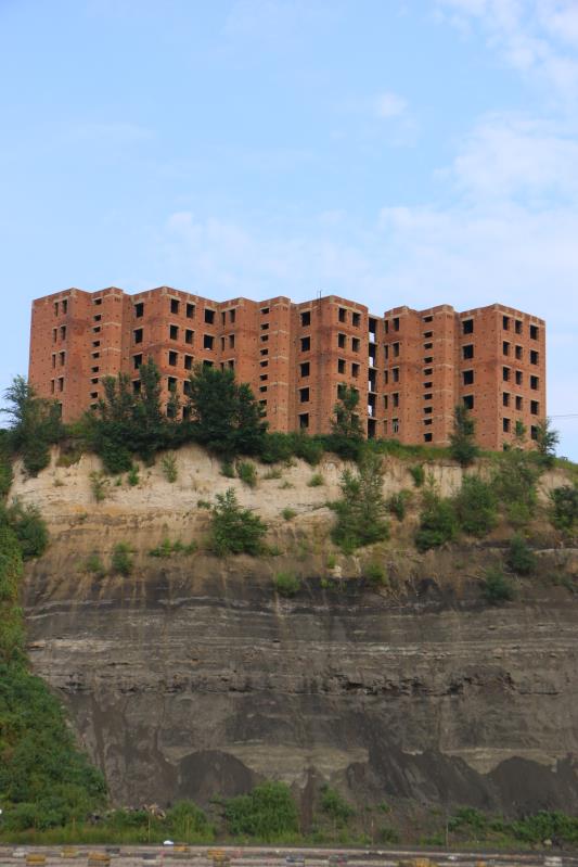 9月5日,举办草莓音乐节的废弃矿坑,黑色的煤层在山体上留下痕迹,上方有一处烂尾楼。新京报记者杜寒三摄