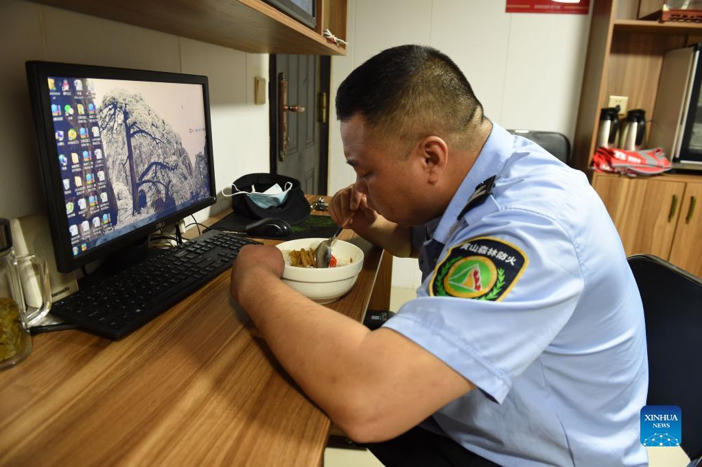 Hu Xiaochun has lunch in the Huangshan Mountain scenic area in east China's Anhui Province, Sept. 26, 2021. Huangshan Mountain, one of the most famous scenic spots in China, is a UNESCO World Heritage site in east China's Anhui Province and a world geopark. Greeting Pine is a famous landmark in Huangshan Mountain. The tree, growing out of the rocks with a long branch extending over the mouth of a cave, got the name mainly because it appears to be greeting anyone who arrives at the scene. It is believed to be between 800 and 1,000 years old. To protect the tree, the local government has introduced a system of designating guardians or rangers for patrolling the tree around the clock. The first guardian was appointed in 1981. The tradition has been going on ever since. Hu Xiaochun is one of the guardians of the Greeting Pine. In 2010, Hu took over the post from his predecessor. He patrols around the Greeting Pine every two hours, observing subtle changes in branches, leaves and bark, as well as the supporting frames and cables. Hu records the tree growth data every day, and the temperature, humidity and wind speed. His 