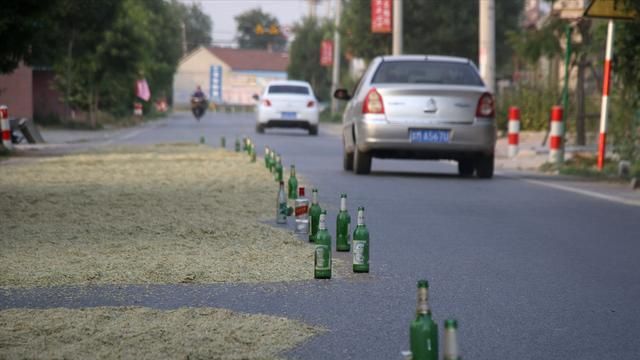 江西村民霸占公路晒粮路边摆满啤酒瓶有人车压爆胎