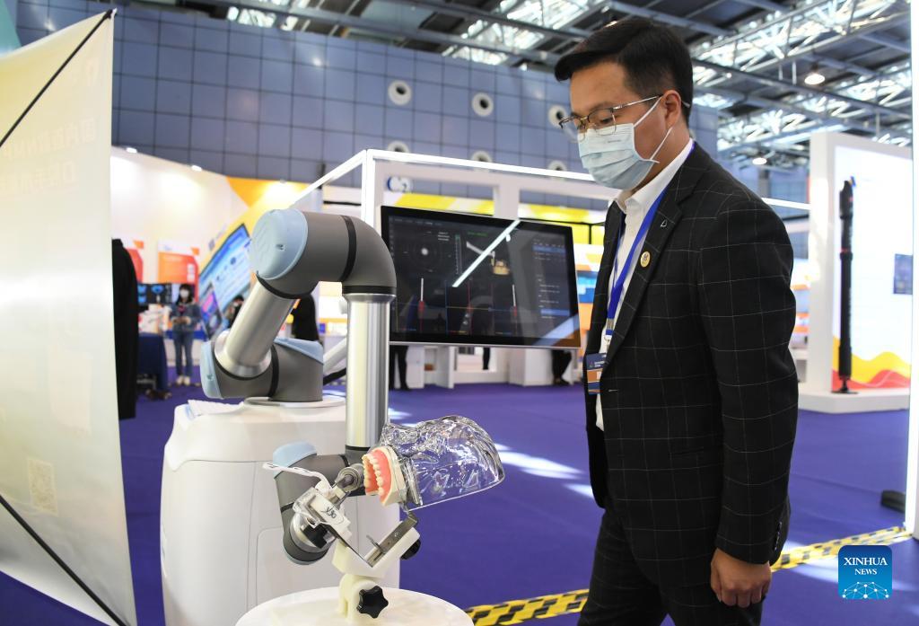 A visitor looks at a robot for oral surgery at an exhibition to mark the 2021 National Mass Innovation and Entrepreneurship Week in Beijing, capital of China, Oct. 19, 2021. The 2021 National Mass Innovation and Entrepreneurship Week was opened on Tuesday. (Xinhua/Ren Chao)