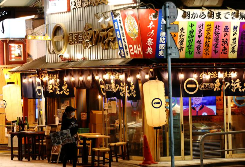 日本东京,一家饭店的服务员在店外迎客。来源:路透社