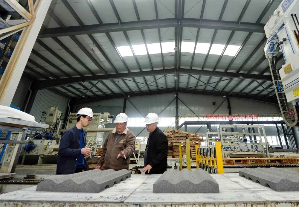 ▲11月4日，王其昌（中）在声屏障吸声板生产厂指导生产