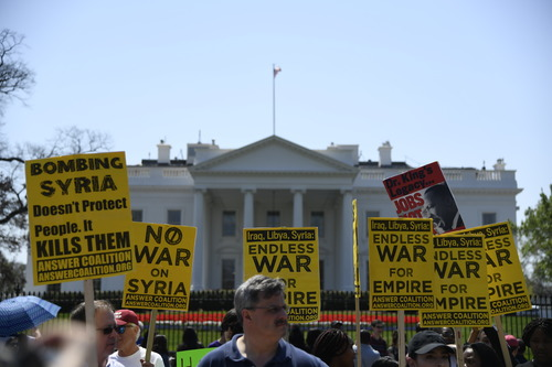 ▲资料图片：2018年4月14日，在美国华盛顿白宫北侧，人们手持标语抗议对叙利亚进行军事打击。新华社记者 杨承霖 摄