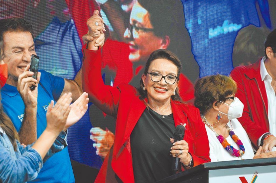 卡斯特罗（中）被她的竞选伙伴纳斯拉亚举起手，当地时间11月28日自行宣布胜选。图自台媒