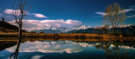 梅里雪山与满天繁星倒映在宁静的湖面上 胡超 摄