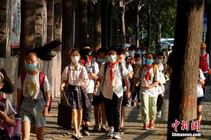 资料图:9月1日,河南郑州,长江东路小学的学生戴口罩有序进入校园。中新社记者 王中举 摄