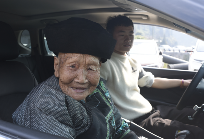 　岩科村92岁的苗家阿婆杨花姐坐上了孙子的小轿车