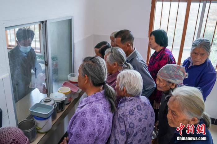 资料图:广西隆安县东信村“爸妈食堂”内,老人们排队取餐。 中新社记者 陈冠言 摄