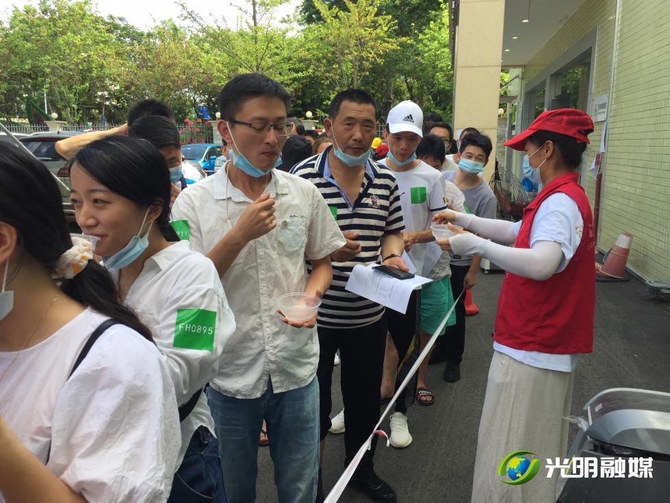 志愿者给排队接种的市民送上糖水。