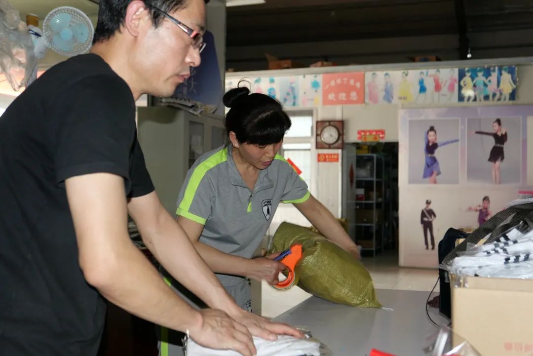 ▲徐伟和妻子赵金平在打包货物,背后的墙上贴着“梦想多大,就能飞多高”的牌子。