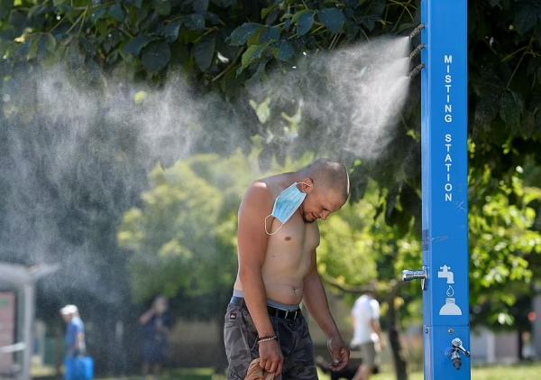 温哥华一男子在“喷雾站(misting station)”冲凉 图源:路透社