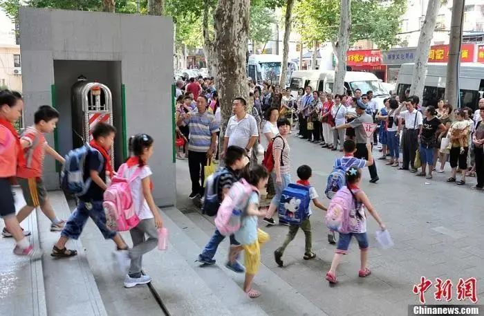 资料图：武汉一小学门外等待学生放学的家长们。中新社发 张畅 摄