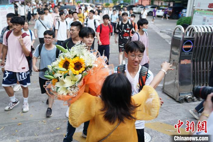 資料圖:6月8日,廣西南寧第二十九中學考點外,考生家長捧着花與考生擁抱。陳冠言 攝