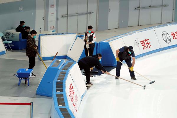 “相约北京”速滑测试赛期间，国家速滑馆的专业志愿者协助工作人员清理冰面。 摄影 崔峻