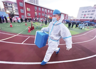 12日,一位工作人员迅速将采样标本从南开区东方小学采样点转运至核酸检测基地。