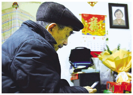  1月19日，金性勇坐在家中，墙上是爱人的遗像。 本报记者郑梦雨摄