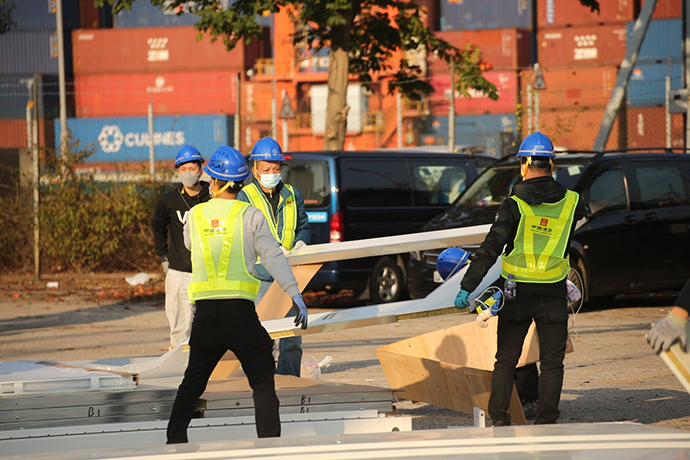 2月23日，香港青衣社区隔离及治疗设施建设工地，施工人员正在齐心协力的装卸材料，与时间赛跑。中国建筑国际集团 供图