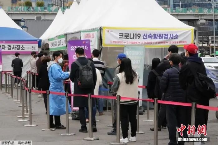 资料图:当地时间2022年3月17日,一名医务人员在韩国首尔的一个临时检测点指导等待新冠病毒检测的人。