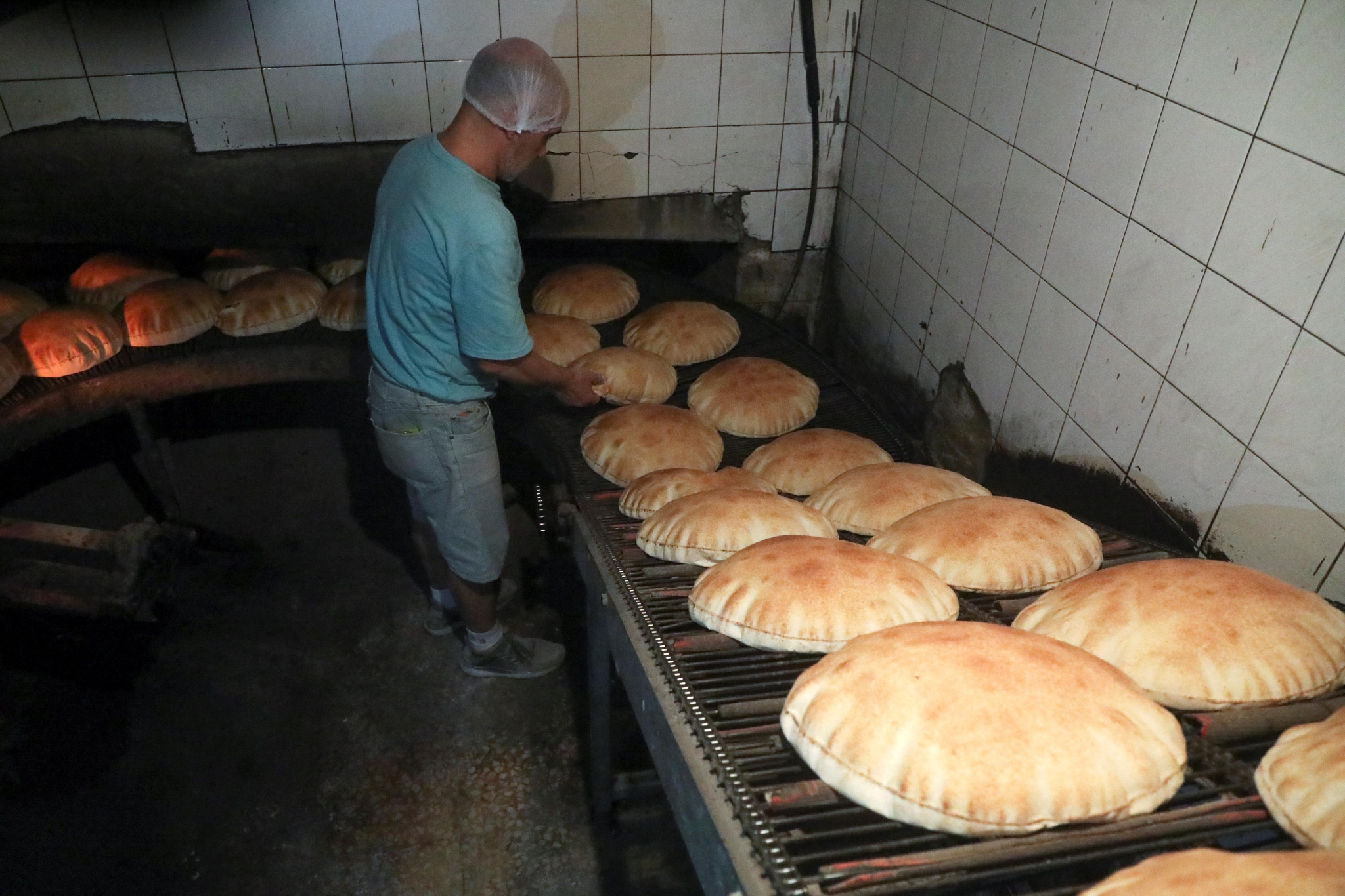 3月8日，黎巴嫩贝鲁特，工人站在面包店新鲜出炉的面包旁，受俄乌冲突影响，黎巴嫩物价飙升。/IC photo