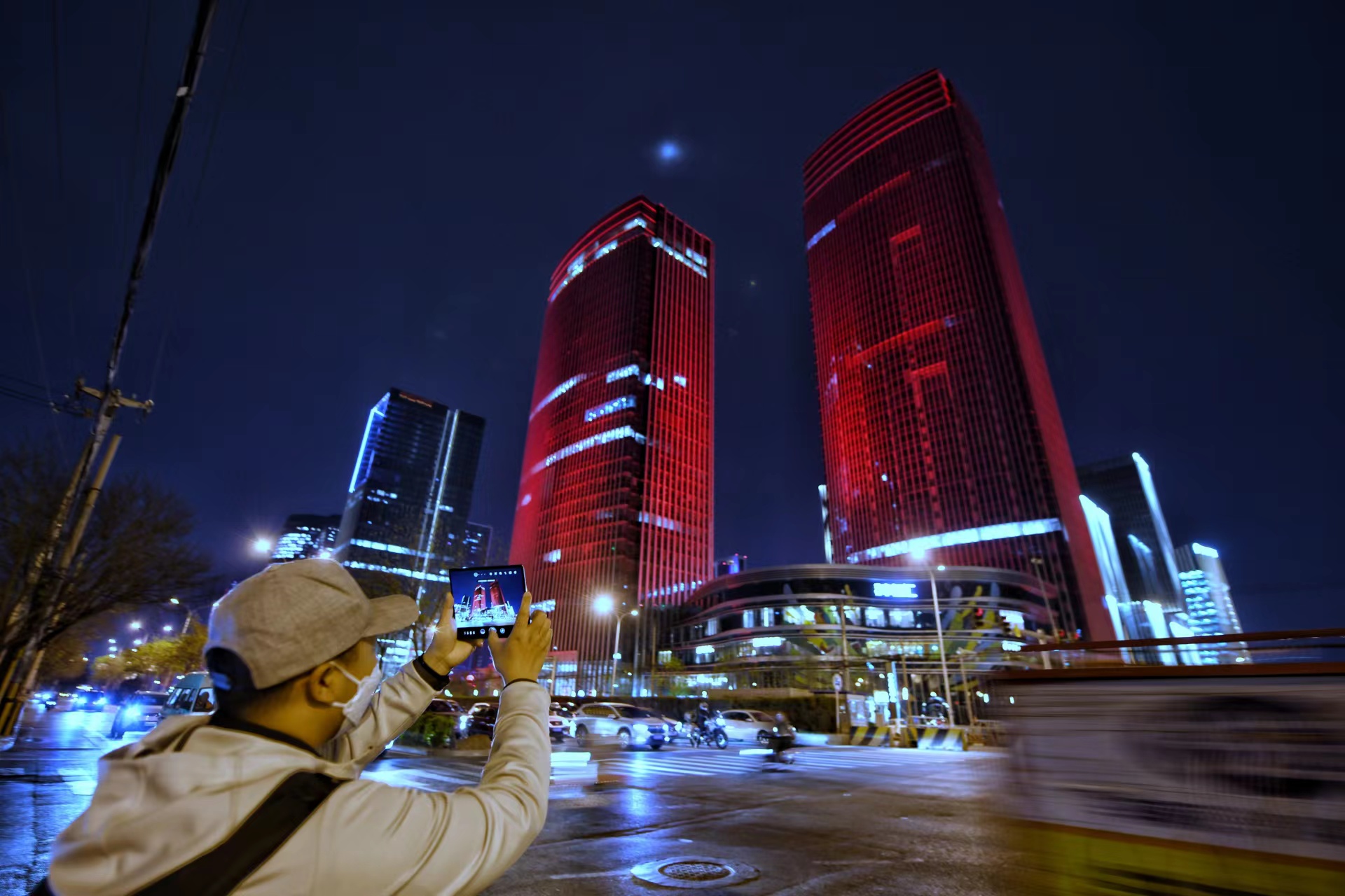 4月13日，一位行人正在拍摄丽泽金融商务区夜景。 新京报记者 陶冉 摄