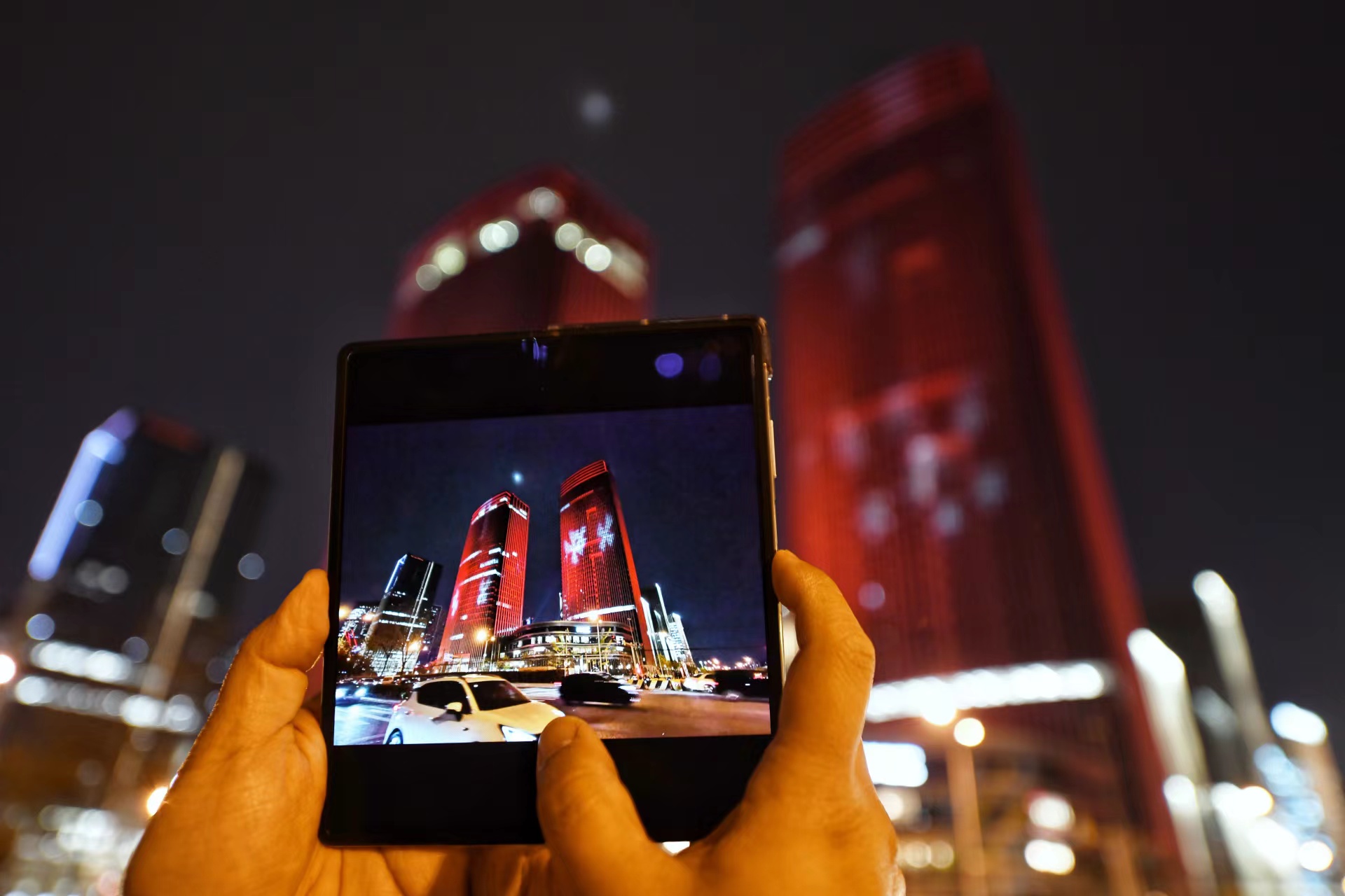 4月13日，行人向记者展示拍摄的丽泽金融商务区夜景图片。 新京报记者 陶冉 摄