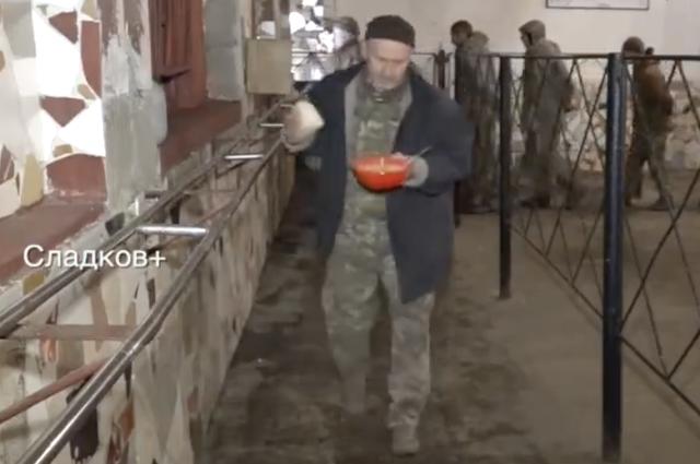 网传乌军战俘在俄军开设的食堂中排队领取麦片奶粥和面包等餐食的视频截图